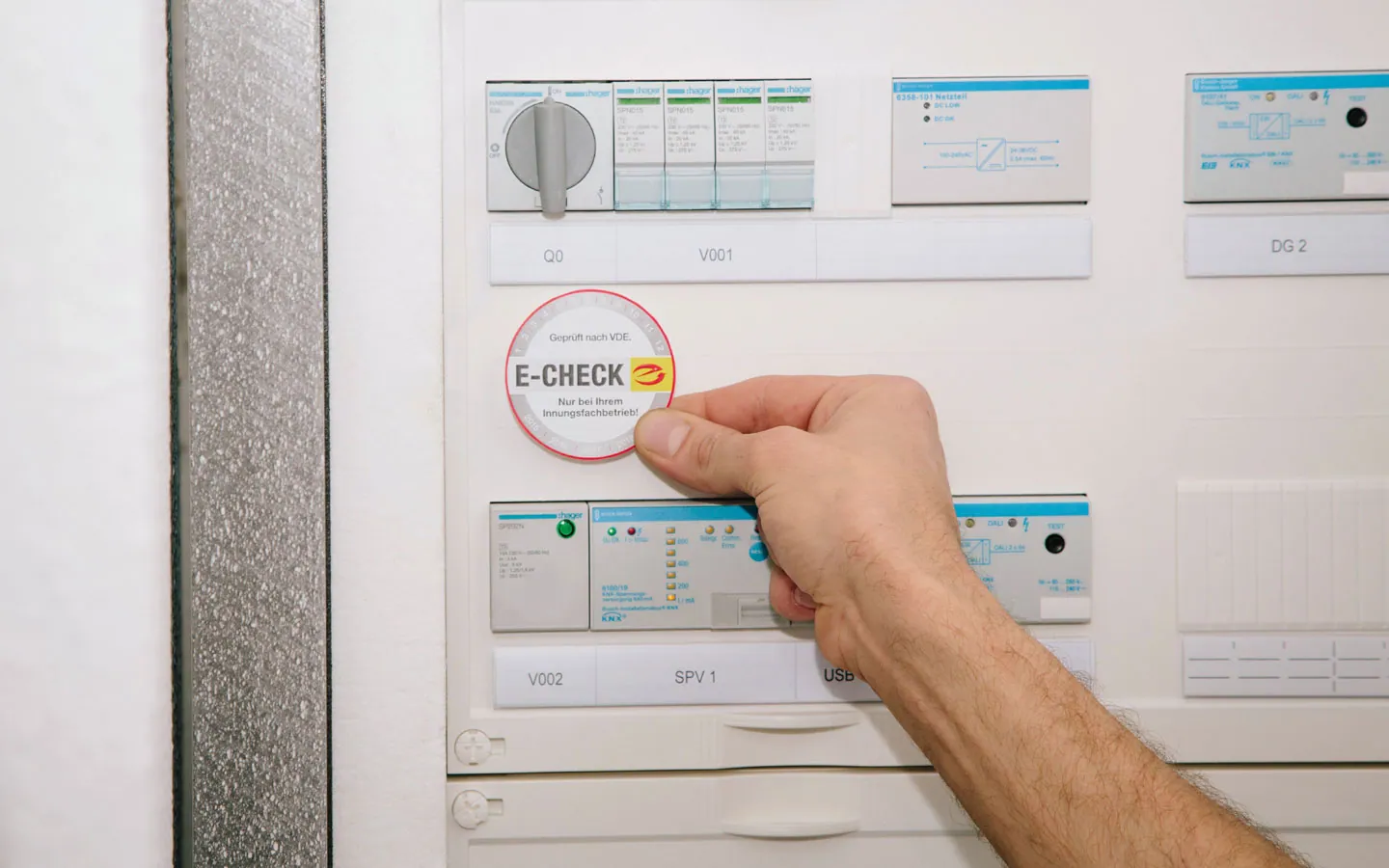 E-CHECK - Mitarbeiter klebt in der Verteilung die E-CHECK Plakette an · Finke Elektro