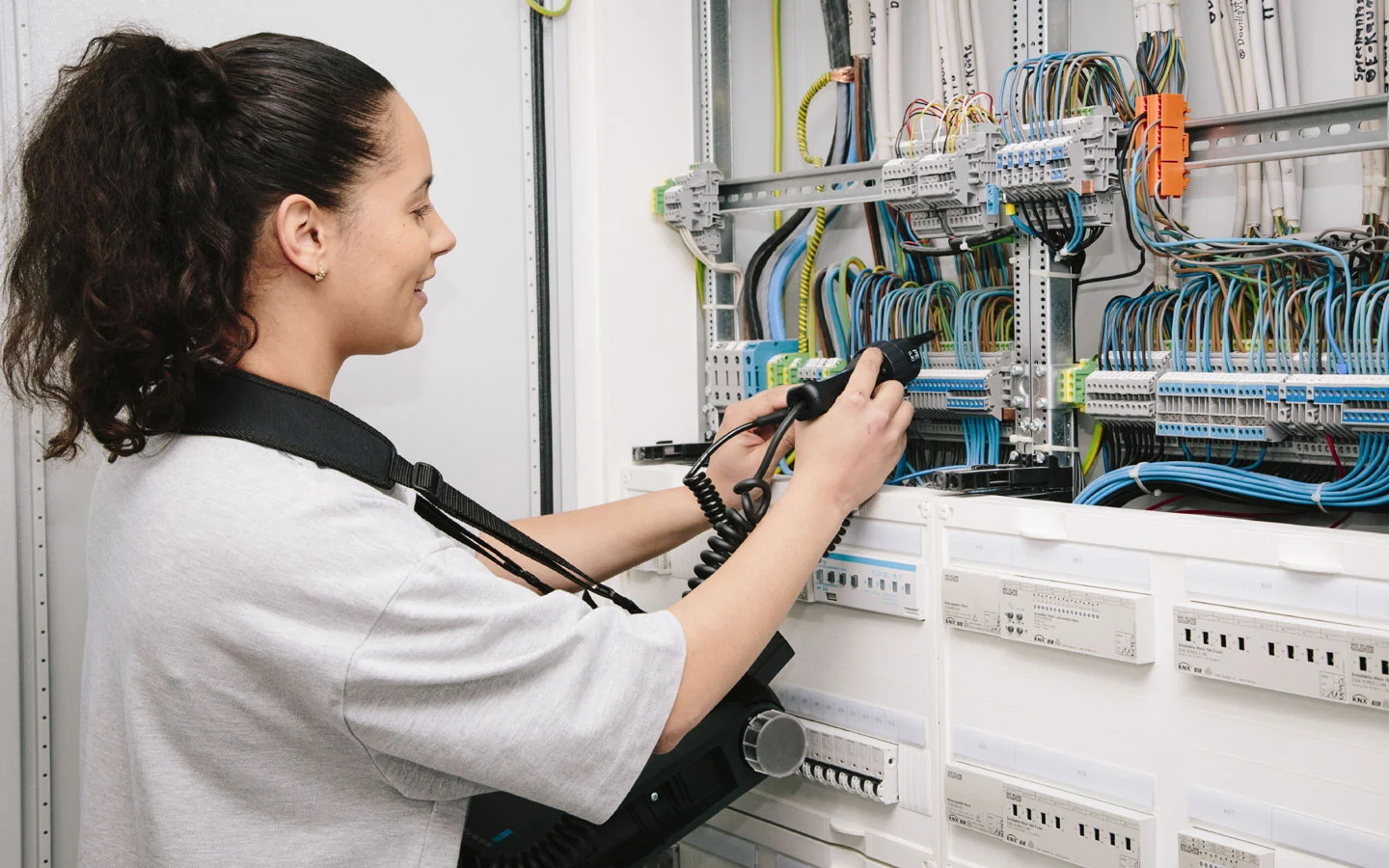 E-CHECK - Mitarbeiterin prüft im Schaltschrank mit einem Meßgerät · Finke Elektro