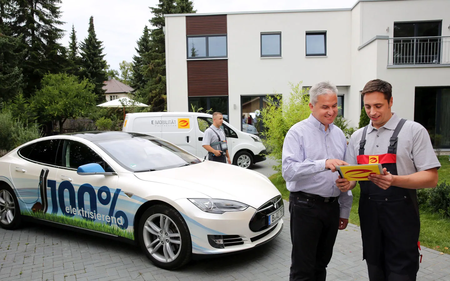 E-Mobilität - Mitarbeiter mit Kunden vor Elektrofahrzeugen 100% elektrisch · Finke Elektro